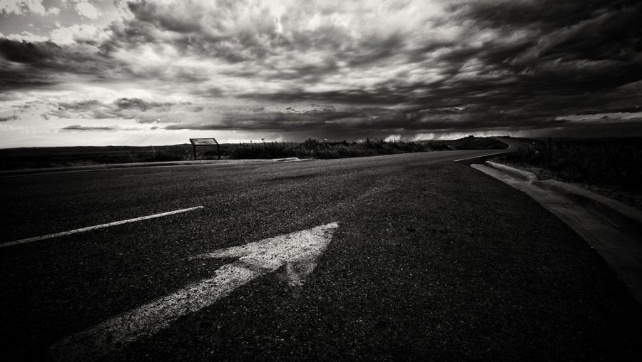 Photo d'une route sombre avec une flèche de signalisation allant vers l'avant