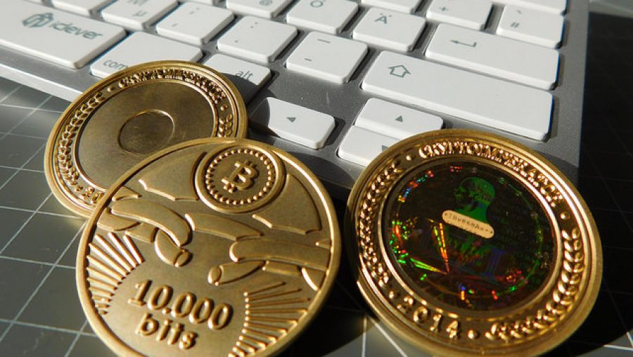 Trois pièces de monnaie (dont une sur laquelle est gravé le symbole Bitcoin)