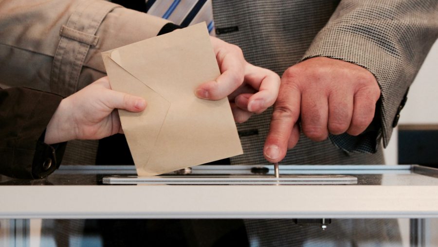 Personne déposant dans une urne un bulletin de vote