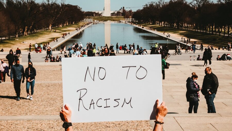 Une personne brandit une pancarte sur laquelle est inscrit : "say no to racism"